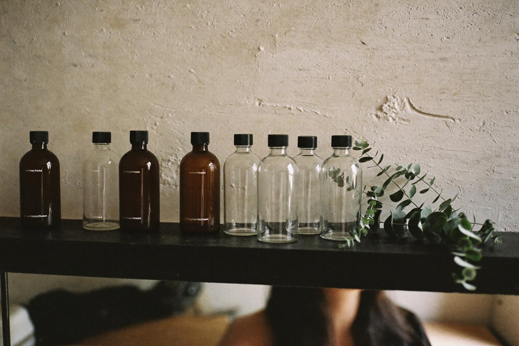 A hand holding a refillable glass apothecary bottle against a lime-wash wall